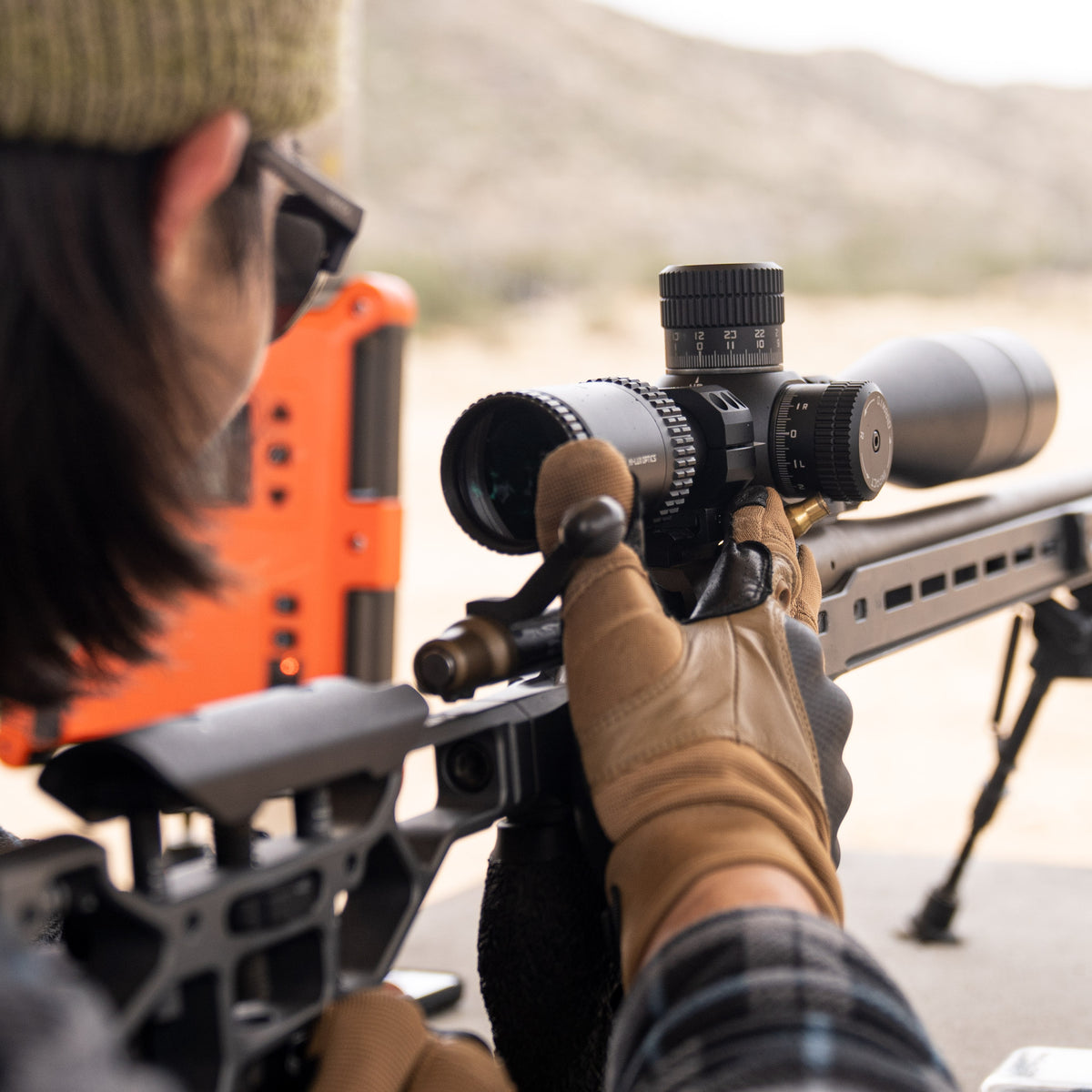 A PR5 5-25X56mm scope mounted atop an MDT chassis and Remington 700 on the bench