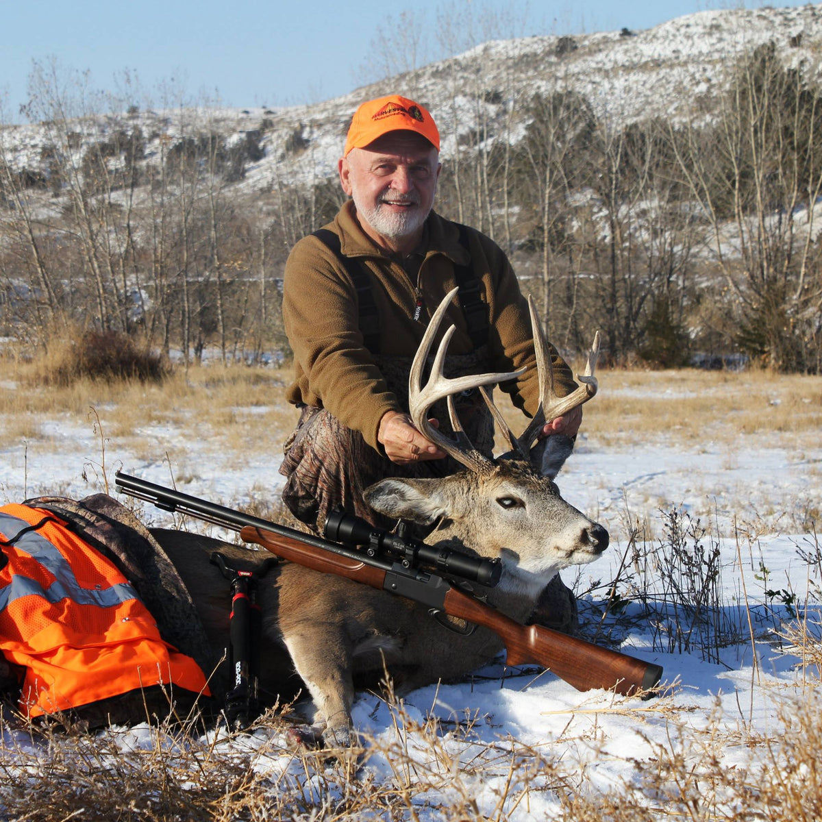 Toby Bridges sits with a buck and a rifle after a successful hunt